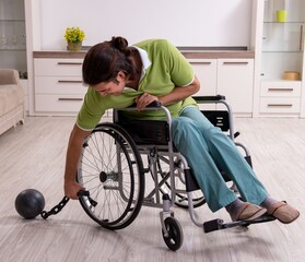 Young male invalid in wheel-chair suffering at home