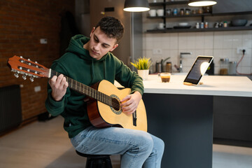 Obraz premium One young man Caucasian teenager sit at home in room playing guitar