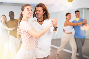 Woman and man practicing social dance moves in pair during group class