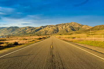 Driving the car through the road to the mountains under blue sunrise sky