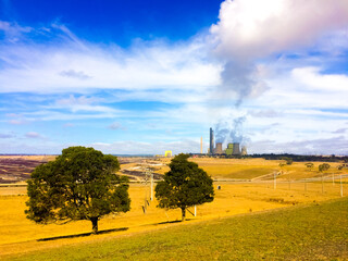 Obraz premium Dirty Co2 from coal powered generator with smoke going to the clean air sky in the middle of an empty field