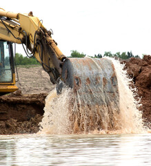 Backhoe digging and splashing in water. © Lu