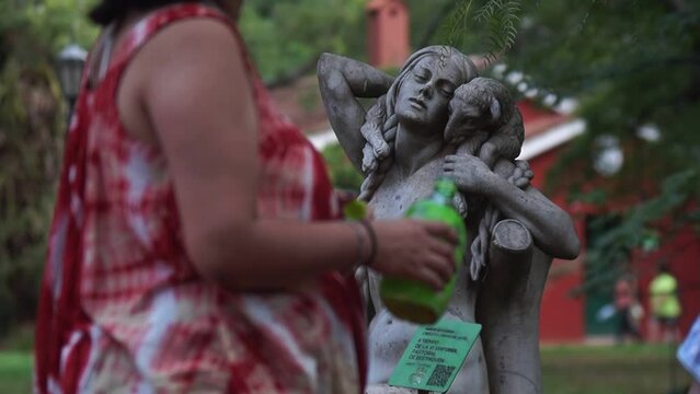 Mujer tomando agua frente a una escultura de una mujer posando
