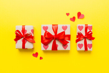 Top view photo of valentine day decorations gift box with red ribbon bow on colored background....