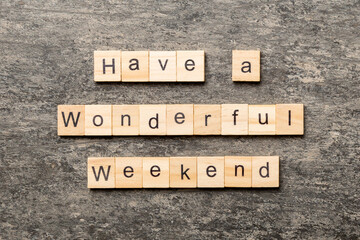 Have a wonderful weekend word written on wood block. Have a wonderful weekend text on cement table...