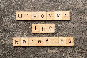 uncover the benefits word written on wood block. uncover the benefits text on table, concept
