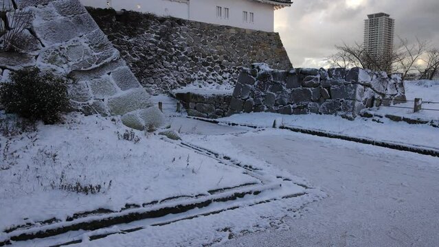 Tilt up to reveal tower atop snow covered stone wall of Akashi Castle