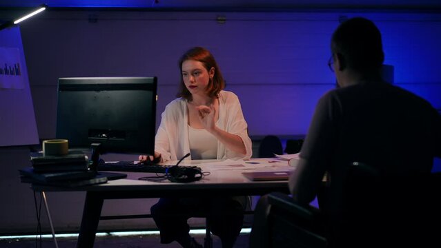 Beautiful concentrated woman analyzing e-market surfing Internet on PC as man in wheelchair analyzing paperwork. Young Caucasian startupers thinking planning business idea in garage indoors