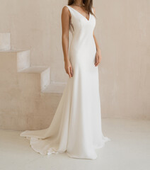 Front view of beautiful bride dressed in a white long wedding dress with deep neckline. Classic...
