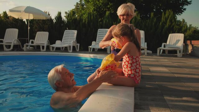 Little girl and grandparents at the swimming pool