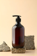 Dark amber glass pump bottle on stone pedestal. Soap gel bottle branding, natural organic spa shampoo container design.