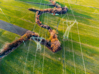 High voltage power transmission towers near a winding creek.  Drone aerial view 