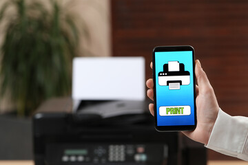 Man using printer management application on mobile phone in office, closeup and space for text