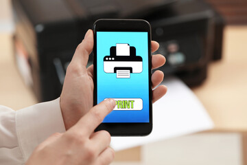 Man using printer management application on mobile phone indoors, closeup. Image on device screen.