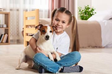 Cute girl hugging her dog on floor at home. Adorable pet