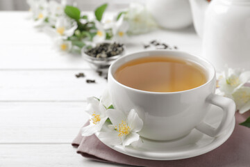 Cup of tea and fresh jasmine flowers on white wooden table