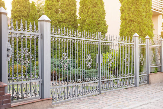 Trees behind beautiful iron fence near pathway outdoors