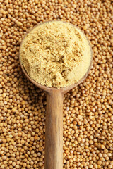 Wooden spoon of aromatic mustard powder on seeds, top view