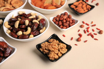 Bowls with dried fruits and nuts on beige background