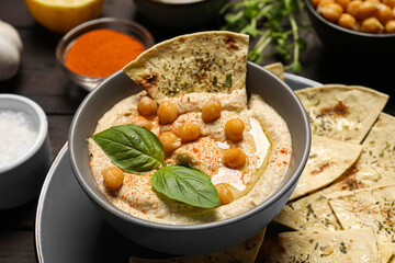 Delicious creamy hummus with chips and different ingredients on table, closeup