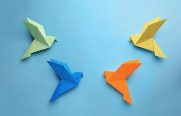 Fototapeta na wymiar Origami art. Colorful handmade paper birds on light blue background, flat lay. Space for text