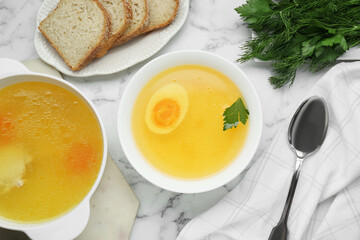 Delicious bouillon served on white marble table, flat lay