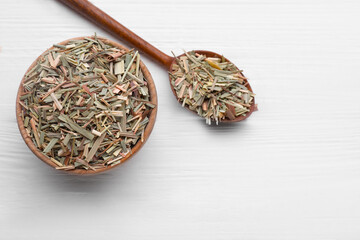 Bowl and spoon with aromatic dried lemongrass on white wooden table, flat lay. Space for text