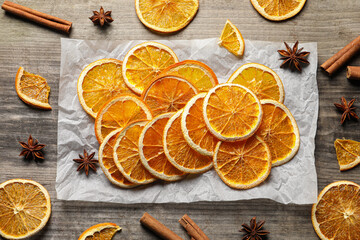 Fototapeta na wymiar Many dry orange slices and spices on wooden table, flat lay