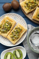 Fresh tasty puff pastry with kiwi served on blue wooden table, flat lay