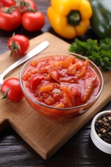 Delicious lecho in bowl and fresh ingredients on wooden table, closeup