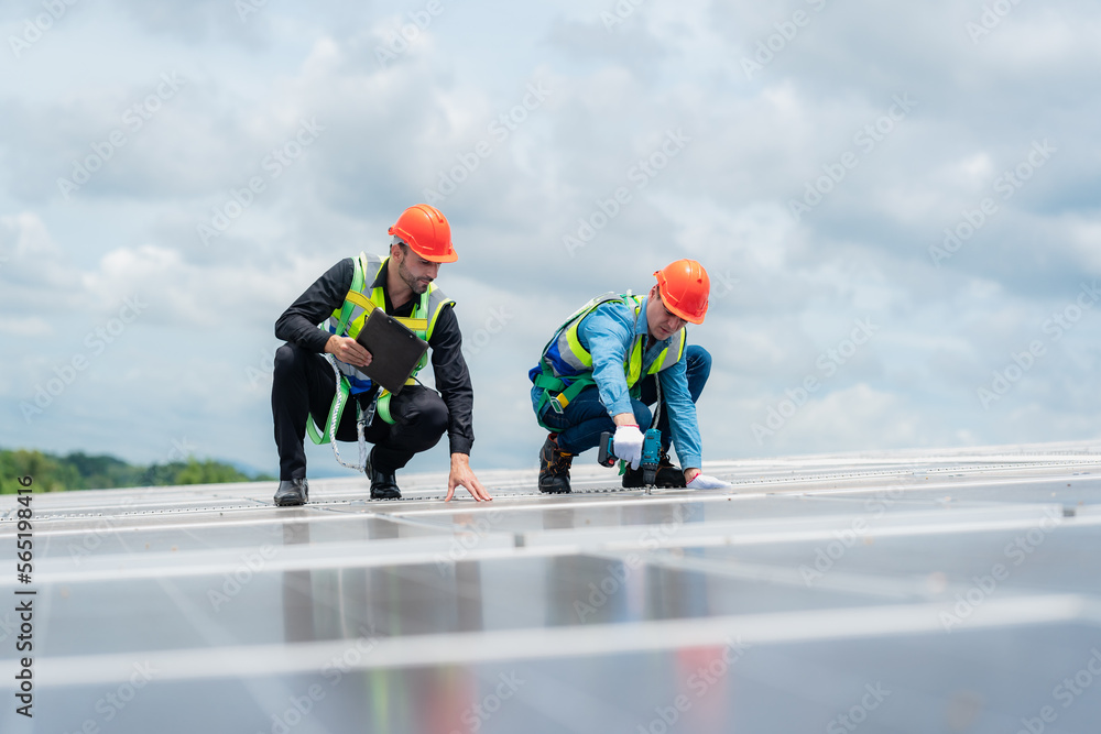 Wall mural technician engineer working on checking maintenance service with solar batteries near solar panels at sunny day in solar power plant station on rooftop, electricity energy of photovoltaic industrial