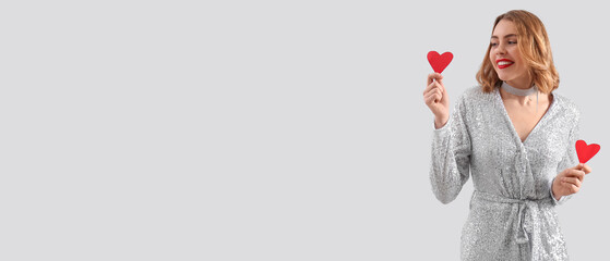 Beautiful young woman with small red hearts on light background  with space for text