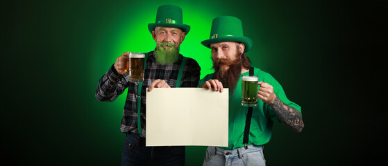 Bearded men with blank poster and glasses of beer on dark green background. St. Patrick's Day celebration