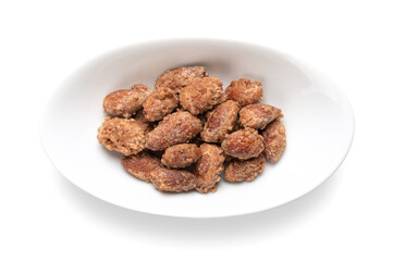 Candied almonds in an oval white bowl. Homemade, in a special way cooked almonds, whole nuts coated...