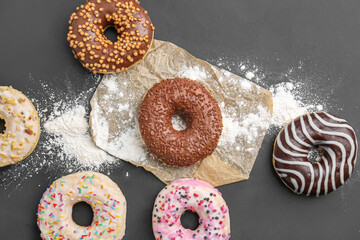 Delicious donuts and sugar powder on dark background