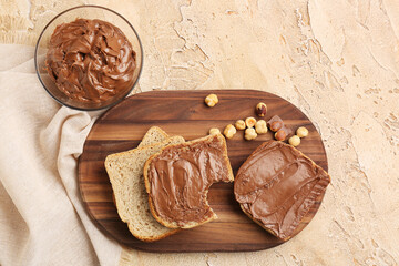 Wooden board of tasty toasts with hazelnut butter and nuts on color background