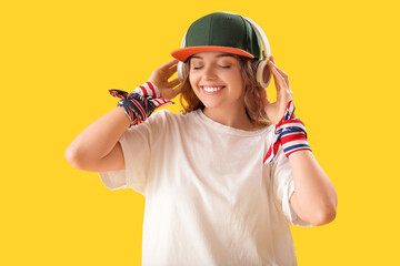 Female hip-hop dancer in headphones on yellow background