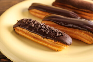 Plate of tasty chocolate eclairs, closeup