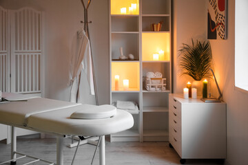 Interior of spa salon with couch, shelving unit and burning candles