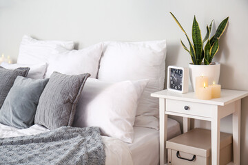 Interior of bedroom with burning candles on end table and houseplant