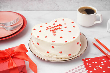 Plate with heart-shaped bento cake and cup of coffee on white table. Valentine's Day celebration