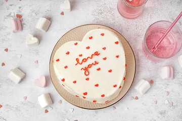 Plate with heart-shaped bento cake and glass of tasty drink on grey background. Valentine's Day celebration