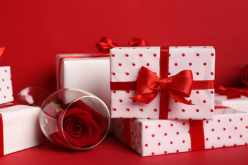 Gift boxes with beautiful bows and rose flowers on red background. Valentine's Day celebration