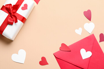 Gift box, envelope and paper hearts on beige background