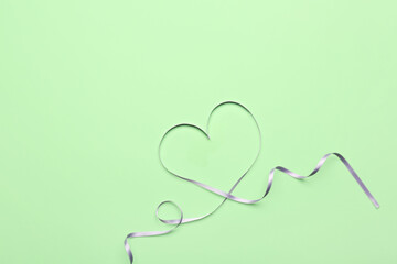 Heart made white satin ribbon on green background. Valentine's Day celebration