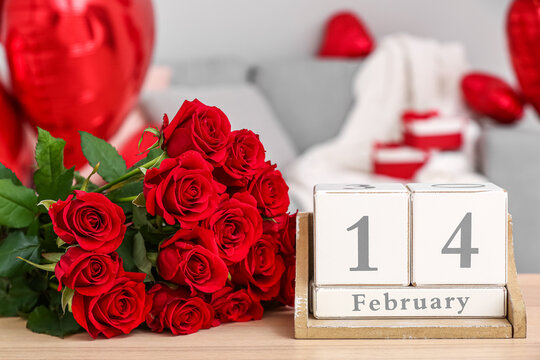 Calendar with date 14 FEBRUARY and roses on table in living room, closeup - Powered by Adobe