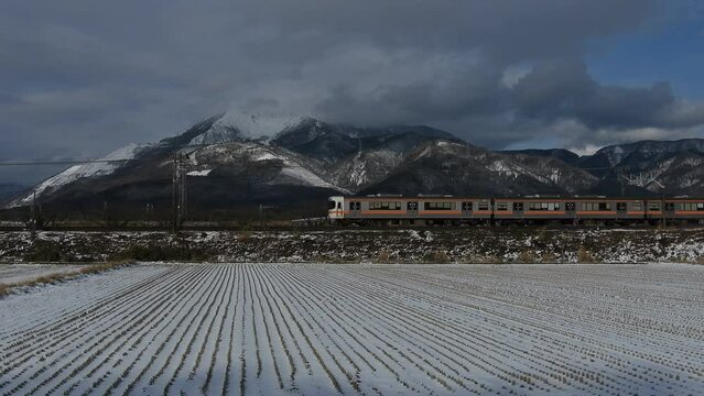 雪の伊吹山をバックに走る313系普通列車