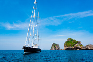 large luxury sailing yacht is anchored off an island in a tropical sea.