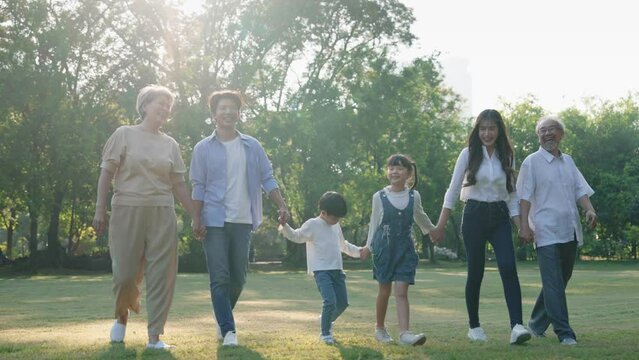 Happy big Asian family on summer walking together in the park, Multi-generation family walking in the outdoor garden