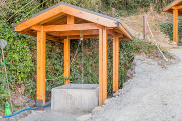 Water well under wooded pavilion beside hiking trail in mountain park.